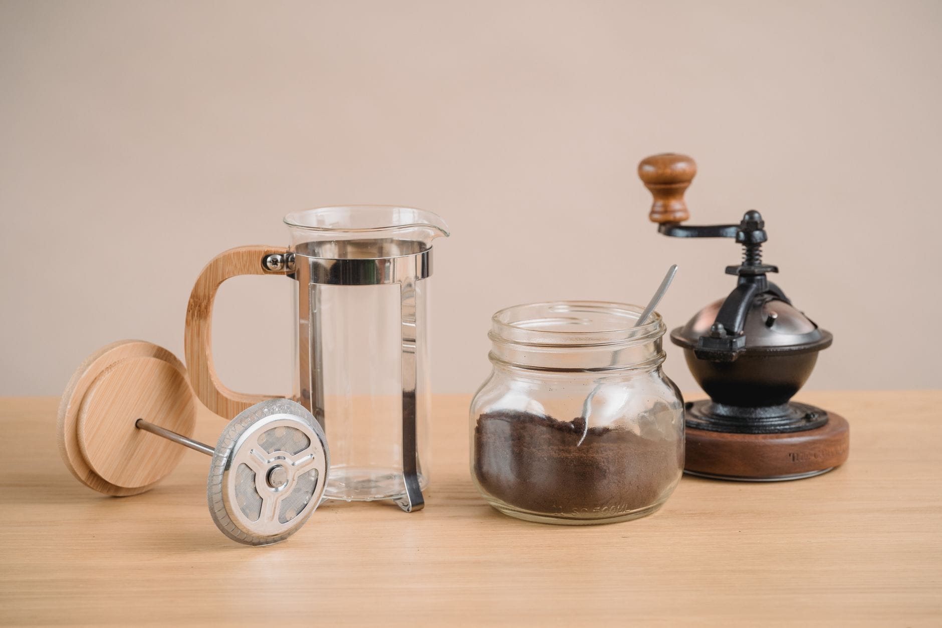 Zaparzacz French press i zabytkowy młynek do kawy na drewnianym stole