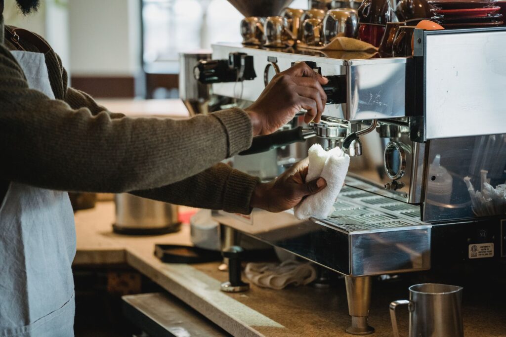 Barista czyści ekspres do kawy w kawiarni